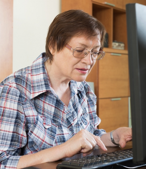 Lady with short hair and specs using a keyboard