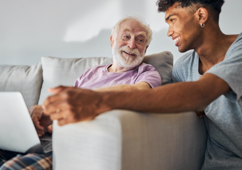 An older and younger man using a laptop together 