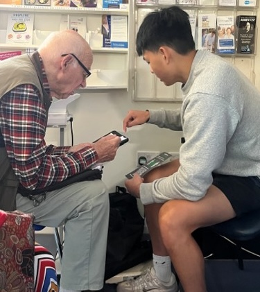 an older man and younger student looking at a phone