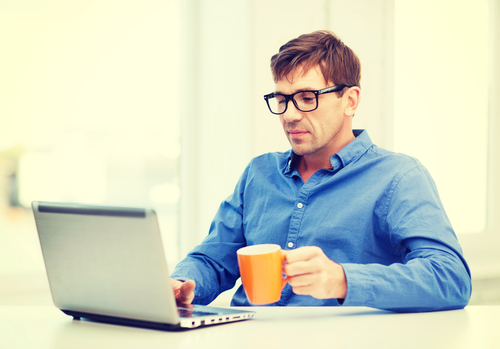 Young man in glasses using laptop