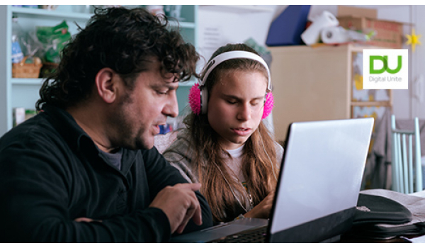 2 people at a computer, the girl has a visual impairment and the man is helping her use the computer