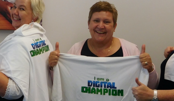 Smiling ladies holding and wearing "I am a digital champion" t shirts