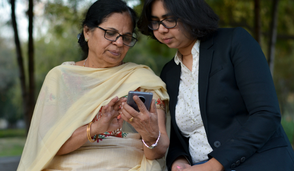 A mum in a sari and a daughter looking at the mum's phone