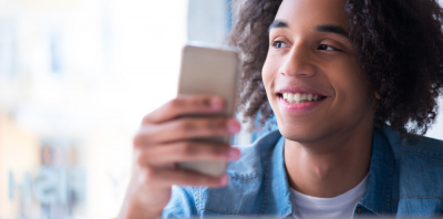 A young man looking at his phone happily