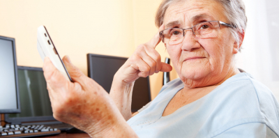 An older lady holding a phone and looking pensive