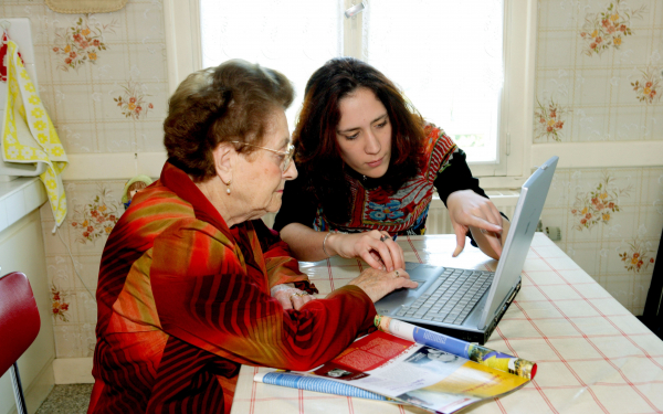 A Digital Champion helping an older lady to use a laptop