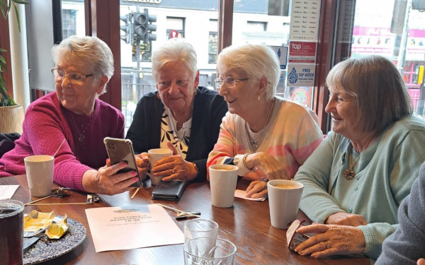 4 ladies round a phone