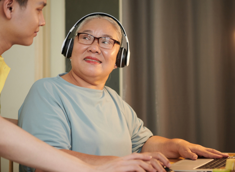 older woman at a computer, young man is helping her