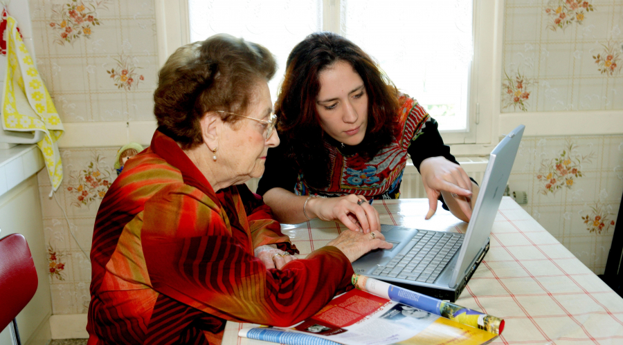 A Digital Champion helping an older lady to use a laptop